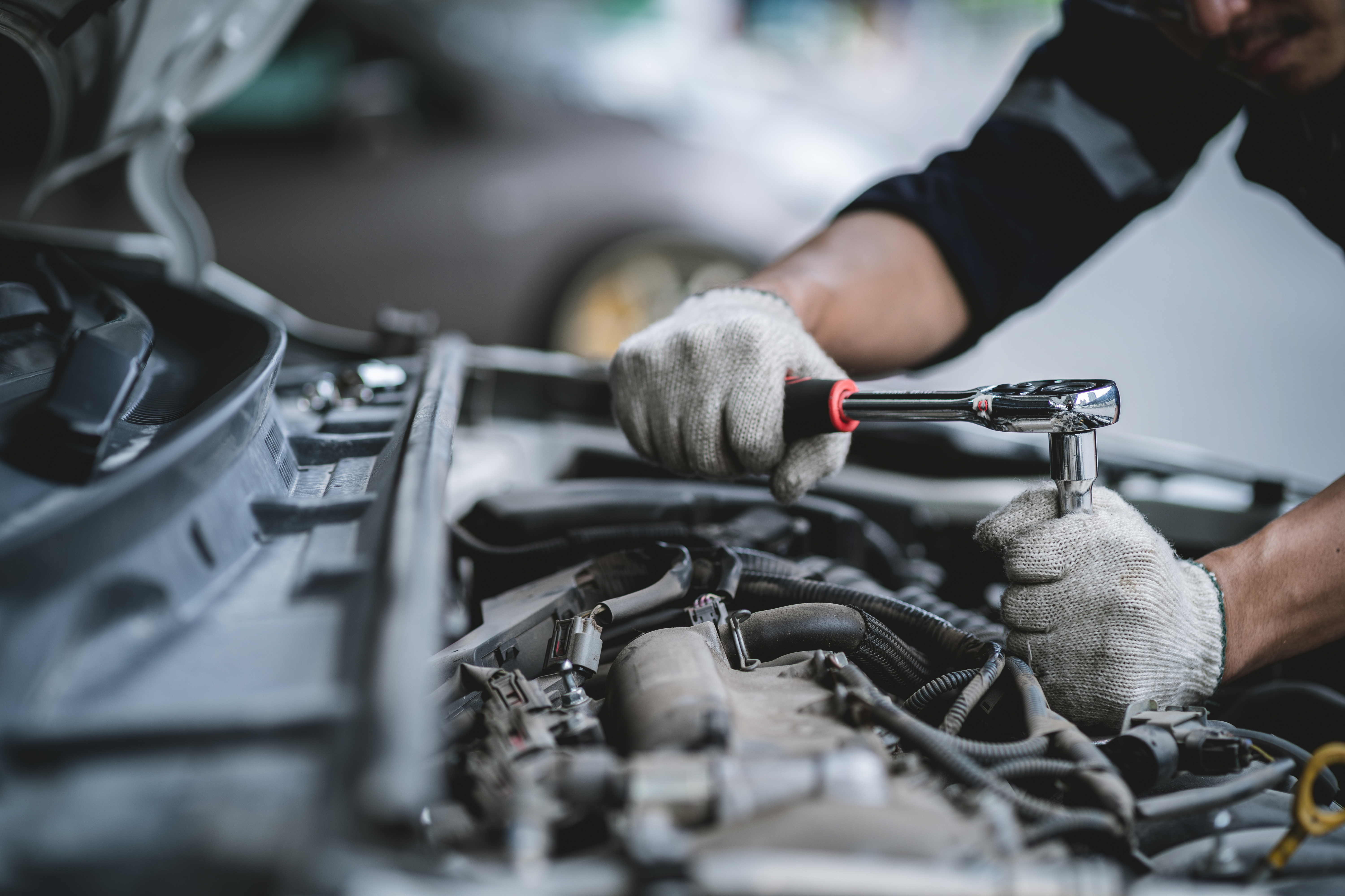 Close-up photo of a car mechanic working on a car engine in a me